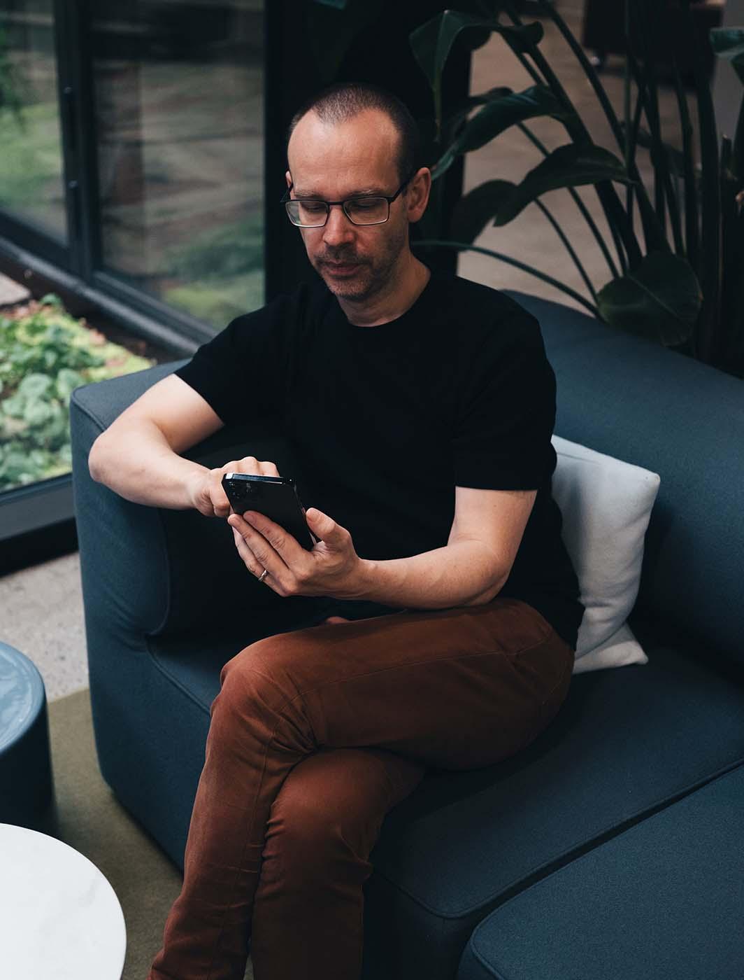 Mann sitzt mit seinem Telefon auf dem Sofa